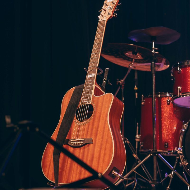 Acoustic guitar and red drums on stage, ready for a live musical performance.